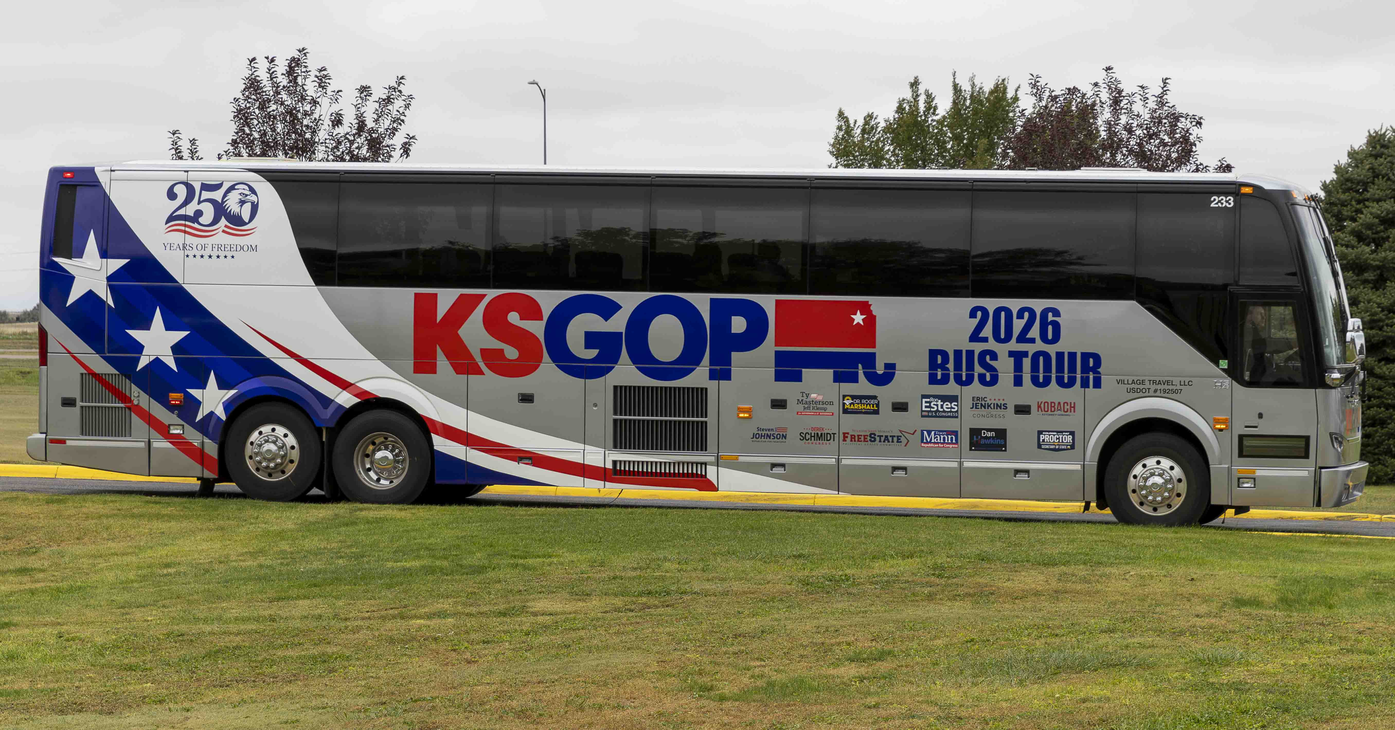 A silver Kansas Republican Party campaign bus parked on the grass at Colby Community College